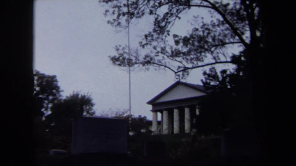 Washington DC 1970 home-movie frame showing a columned park structure through trees and shadowed foreground edges.