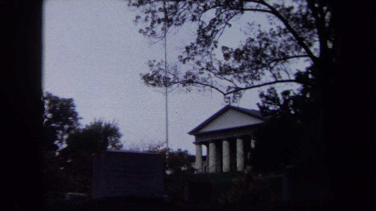 1970 Washington, DC 8mm frame showing a distant columned building, flagpole, lawn, trees, and dark foreground silhouettes.