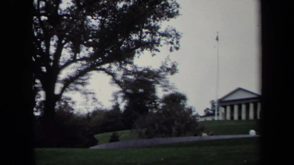 Wide 8mm view in Washington, DC, of a classical columned building on a lawn with a flagpole and trees around it.