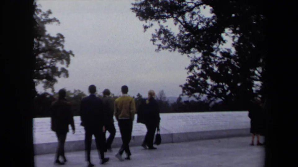 1970 Washington, DC home-movie view of tourists walking past a white memorial wall with trees and a hazy vista in the background.