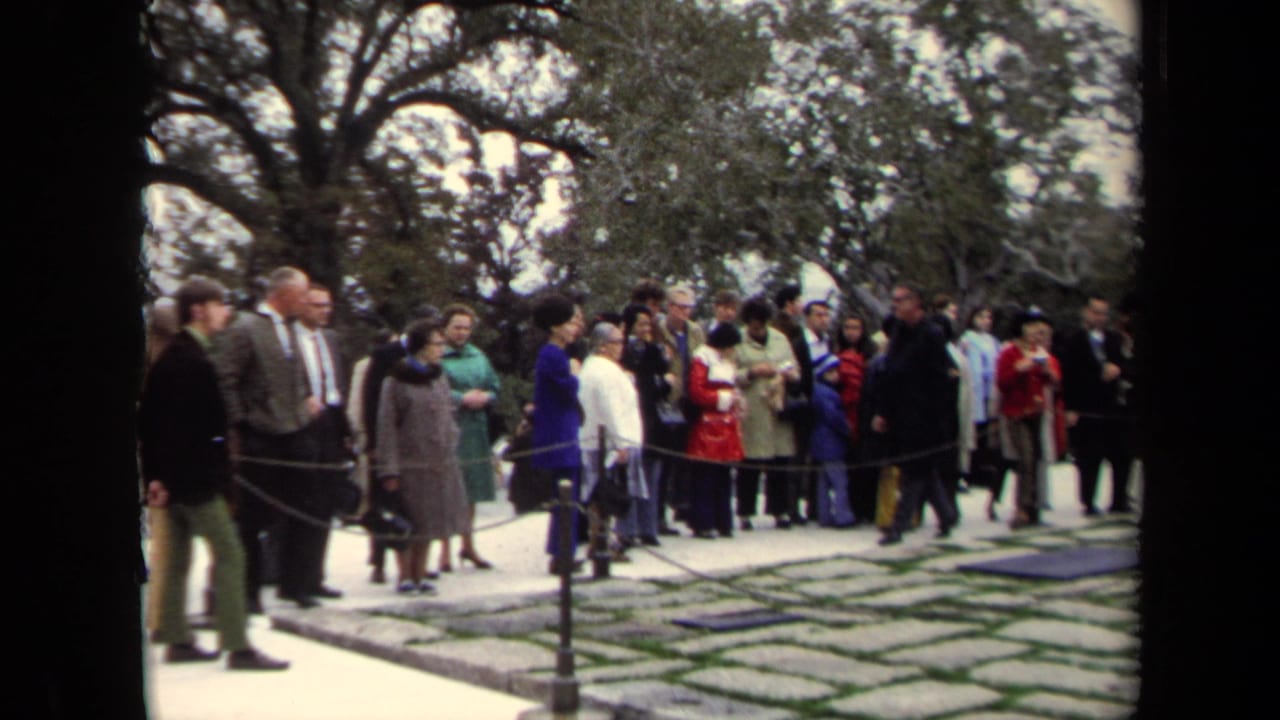 Visitors in period clothing wait or observe behind rope barriers at a Washington, DC memorial site in 1970.