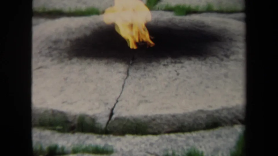 Closer 1970 8mm Washington, DC view of the flame rising from a blackened area on the circular stone fire pit.