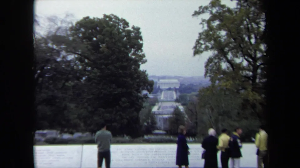 A 1970 visitor-shot Washington, DC frame shows several tourists near a stone overlook, with trees and the Reflecting Pool view receding into the distance.