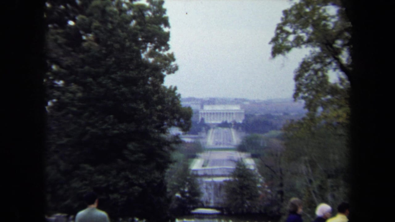 1970 Washington DC home-movie frame showing the Lincoln Memorial and Reflecting Pool through trees from a raised visitor viewpoint.
