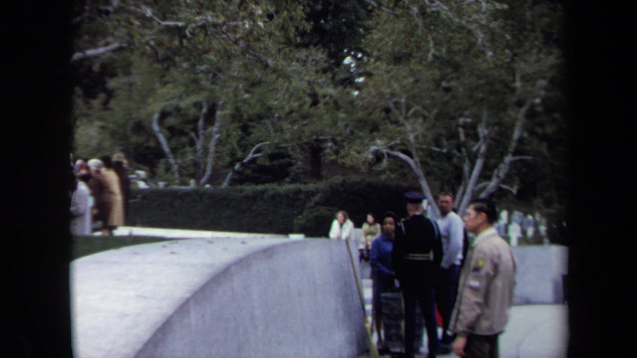 1970 Washington, DC home-movie frame showing visitors beside a curved walkway in a landscaped park setting.