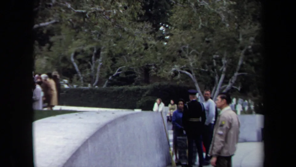 1970 Washington, DC home-movie frame showing visitors beside a curved walkway in a landscaped park setting.