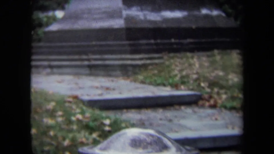 1970 Washington, DC cemetery detail showing the lower stone memorial base near a paved path and autumn leaves.