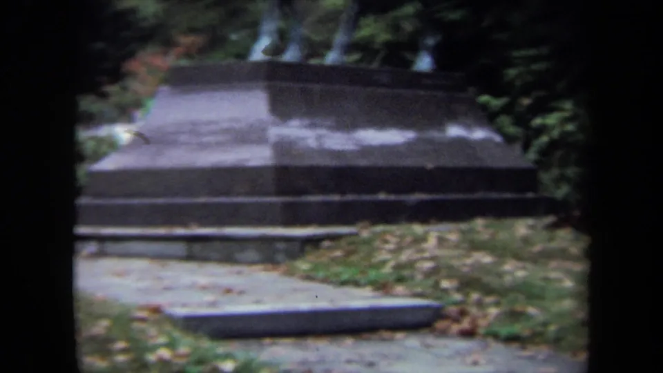 1970 Washington DC 8mm frame showing the base of an outdoor equestrian monument amid trees and autumn leaves.