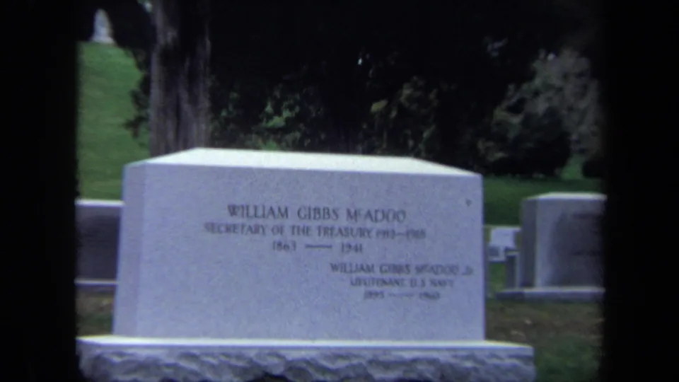 Closer 8mm view of the William Gibbs McAdoo gravestone, with partial inscription visible and headstones behind it.