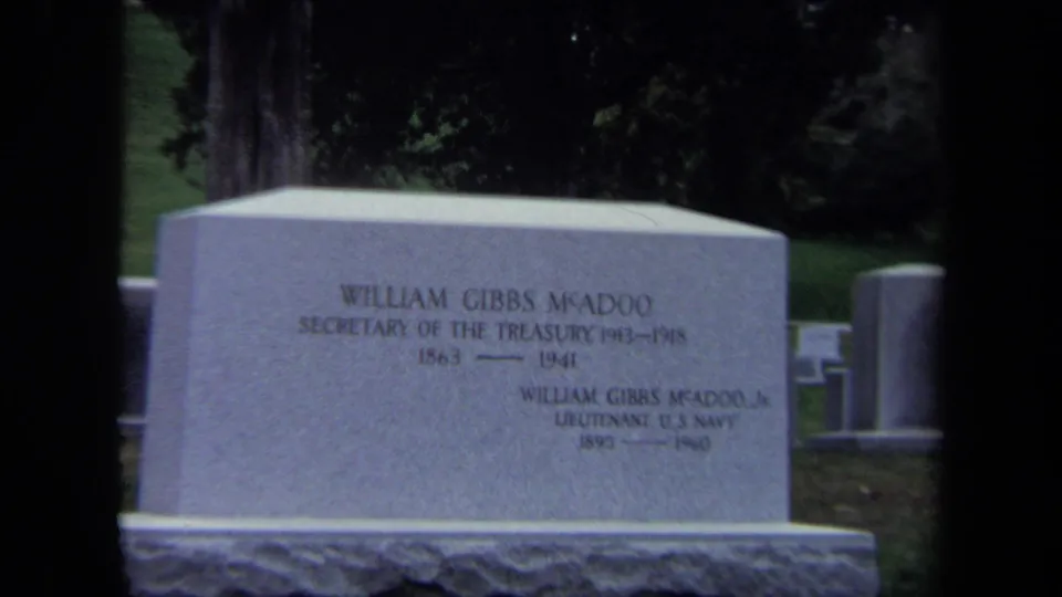 1970 Washington DC 8mm frame showing the William Gibbs McAdoo family headstone with grass and other cemetery markers nearby.