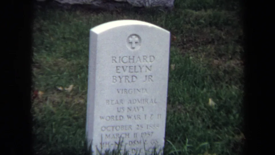 The final 8mm frame centers the Richard Evelyn Byrd Jr. grave marker, with military service text visible but softened by focus and film grain.
