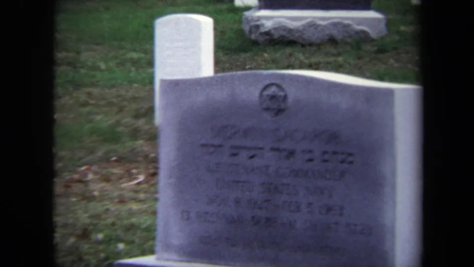 Final 1970 Washington, DC frame holds on the same gray gravestone, with Hebrew text, a Star of David, and military service wording partly softened by focus.