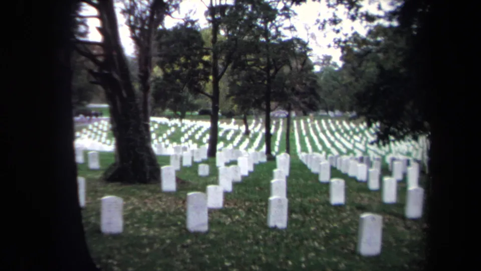 Washington DC cemetery grounds in 1970, showing orderly rows of white headstones framed by dark tree trunks.