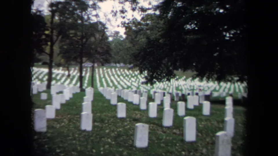 A wide 1970 8mm view of Washington DC cemetery grounds with headstones receding through trees.