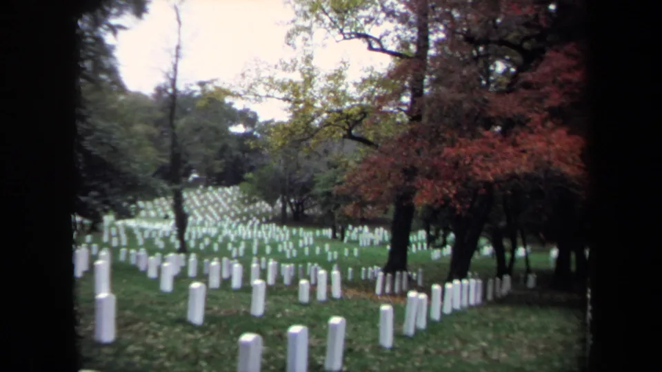 Visitor-shot 8mm view of a cemetery hillside in Washington, DC, with white tombstones and red autumn trees.