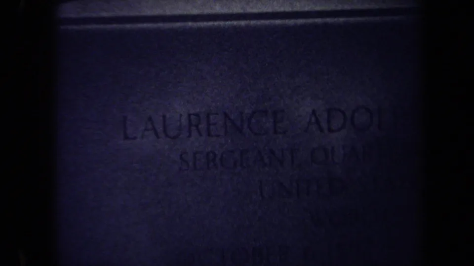1970 Washington DC 8mm close-up of a dim headstone inscription naming Laurence Adolph Steinhart, with Army service text partly visible.