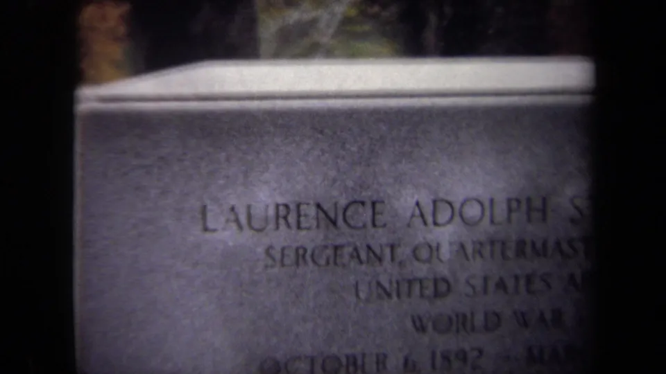 1970 Washington, DC 8mm frame showing a close, soft-focus view of an engraved military tombstone for Laurence Adolph Steinhard.