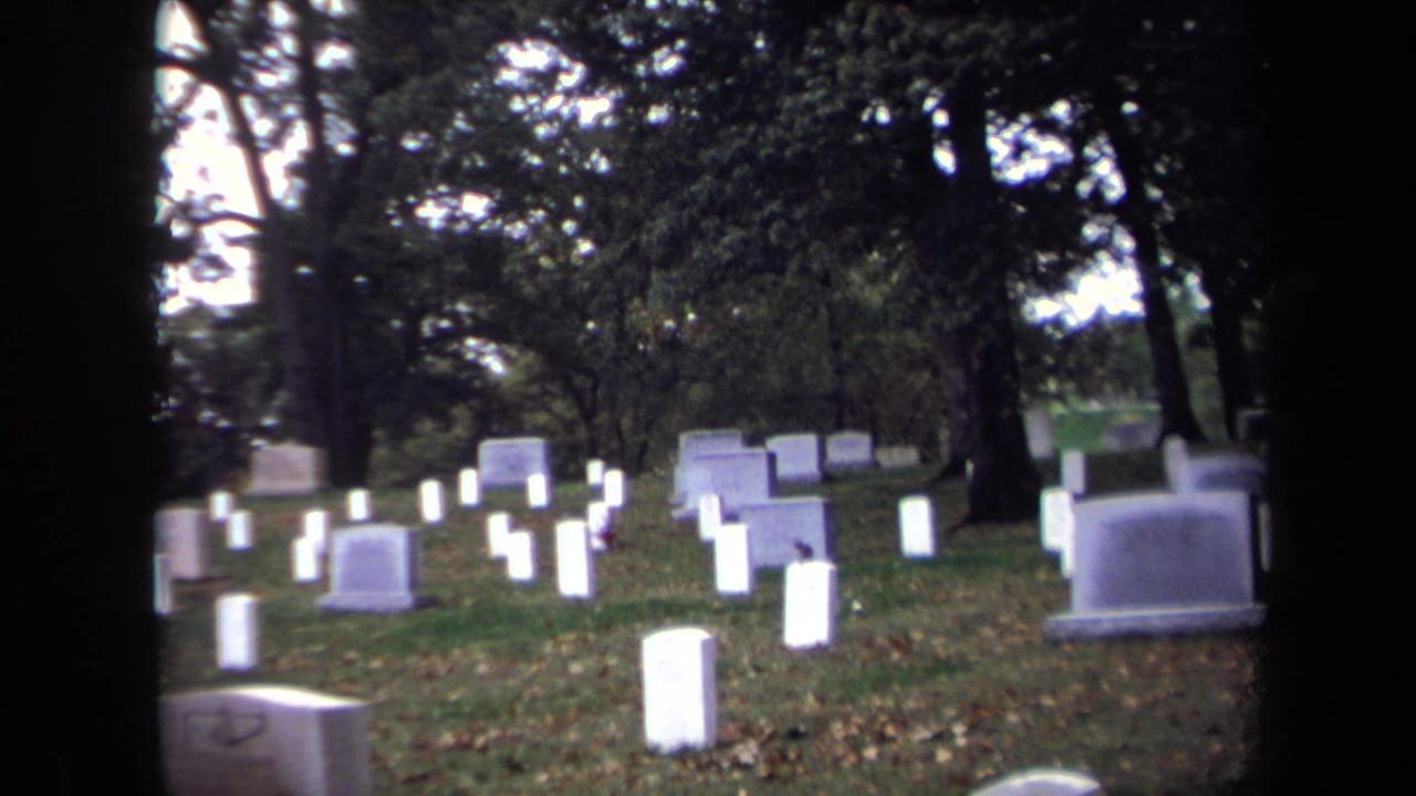 Soft 8mm cemetery view in Washington, DC, showing white grave markers, trees, grass, and dark edges from the film frame.