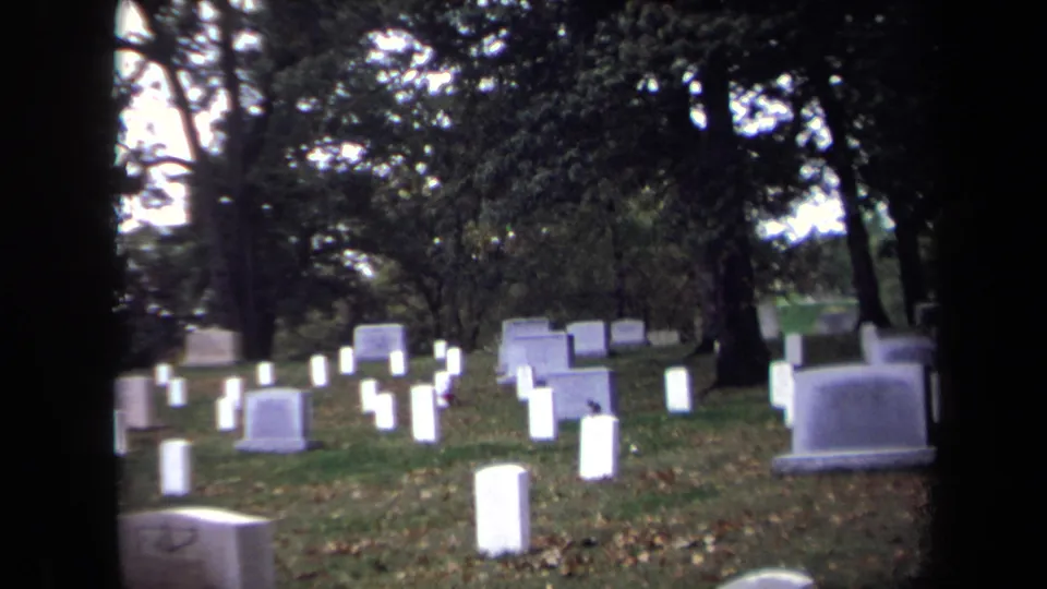 Soft 8mm cemetery view in Washington, DC, showing white grave markers, trees, grass, and dark edges from the film frame.