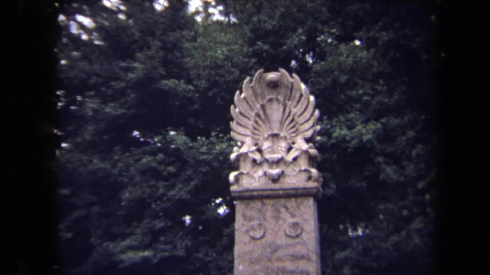 Final 1970 Washington, DC frame holding on the carved stone monument top, backed by dark green park trees.