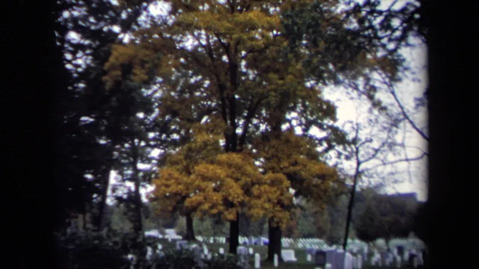 Handheld 8mm view of a Washington DC cemetery in 1970, showing yellow autumn trees and rows of white headstones.