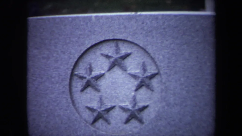 Close-up of a cemetery stone marker in Washington DC with a circular emblem containing five raised stars.