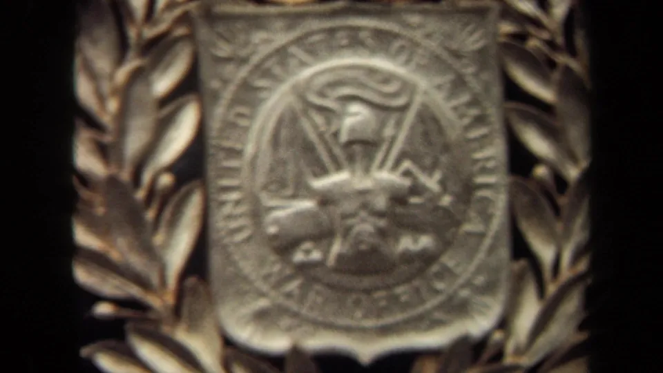 1970 Washington, DC 8mm frame showing a soft close view of a raised metal War Office-style emblem with laurel leaves.
