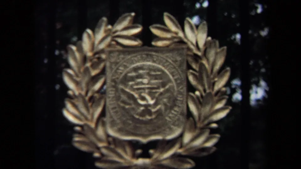 1970 Washington, DC home-movie frame with a metal government-style emblem centered inside a laurel wreath.