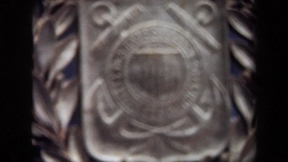 Soft close-up from the 1970 8mm clip showing the Coast Guard shield and surrounding wreath in blurred detail.