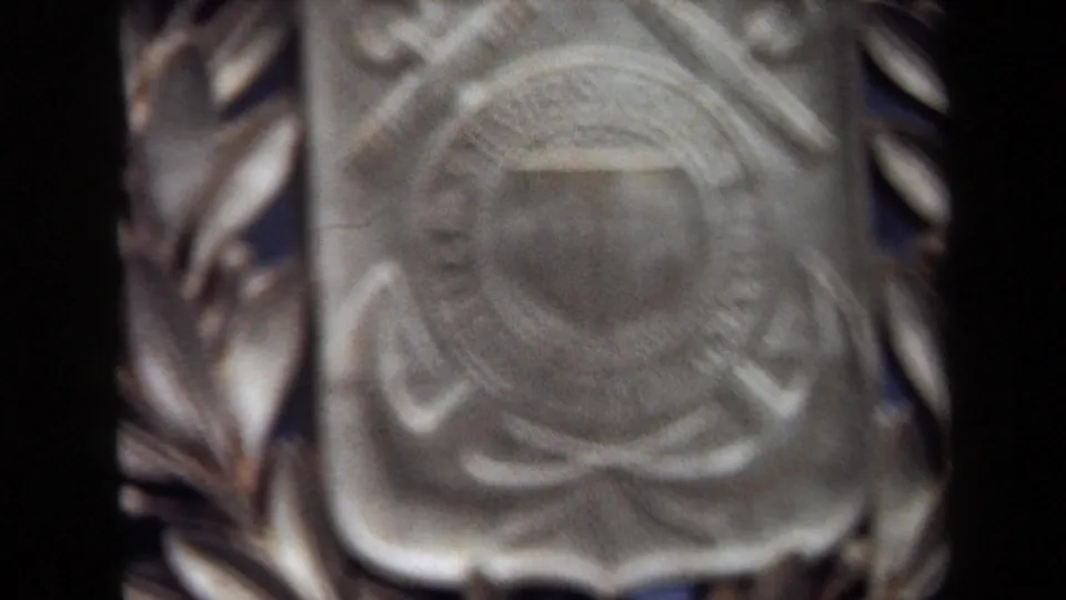 1970 Washington, DC home-movie frame with a blurred close view of the Coast Guard emblem and laurel wreath.