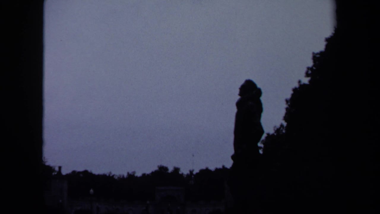 1970 Washington, DC frame with a silhouetted figure or statue near trees, set against a pale overcast sky.