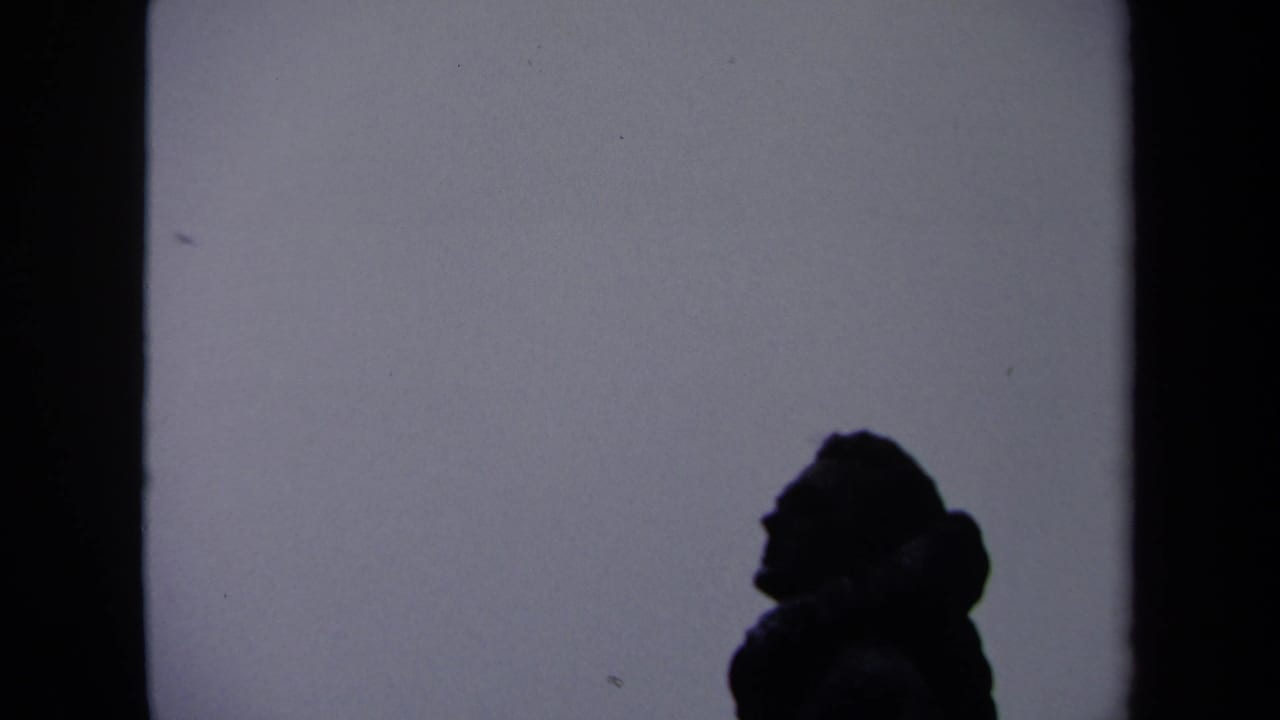 1970 Washington, DC home-movie frame showing a dark human profile silhouette against a pale wall surface.