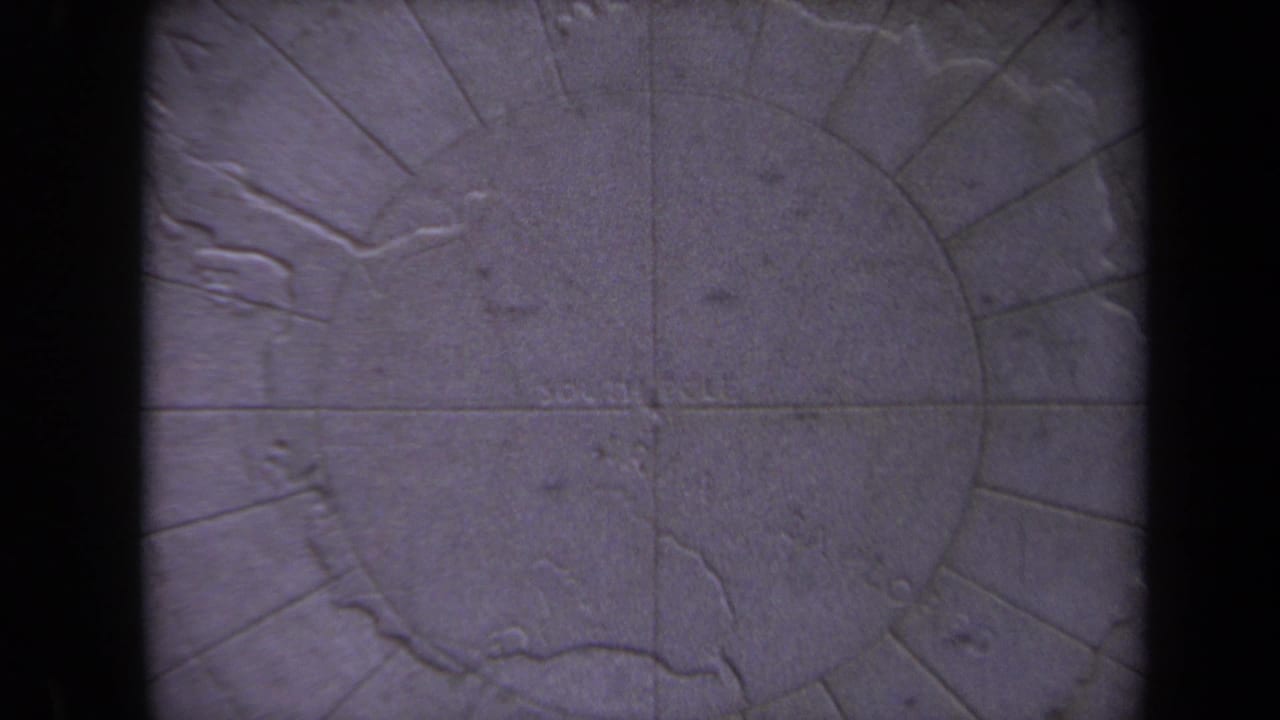 Close view of a carved stone South Pole map with dark vertical bars in the foreground.