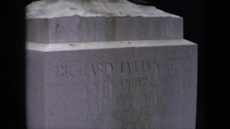 1970 Washington, DC home-movie frame showing the upper portion of Richard Evelyn Byrd's engraved gravestone in soft 8mm focus.