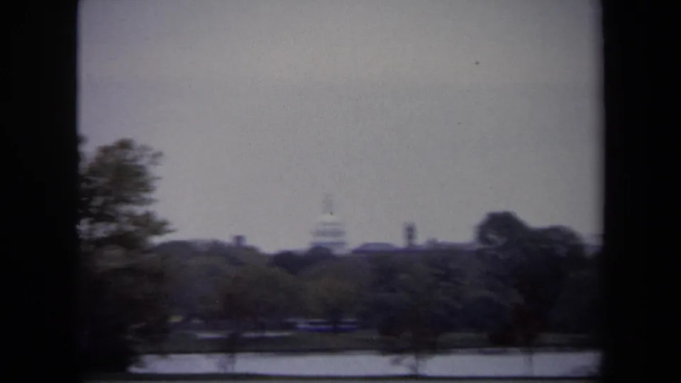 Blurred 1970 Washington DC visitor-shot view of the Capitol dome across a landscaped water area, likely filmed in motion.