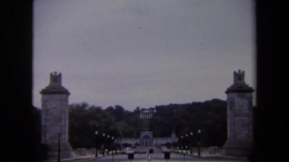 Soft 8mm Washington DC frame from 1970 showing a steady view down a formal road between stone pylons and rows of lights.