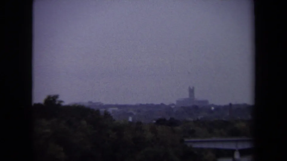 1970 Washington, DC cityscape with trees in the foreground and a distant steeple-like structure on the horizon.