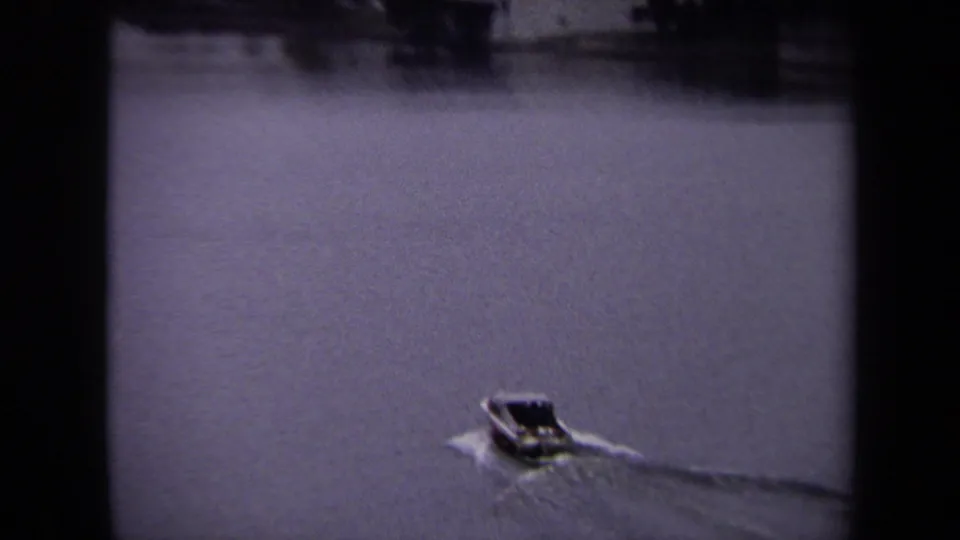 Small speedboat travels across open water in Washington DC, with distant shoreline details softened by the 8mm scan.