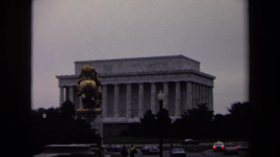 Washington, DC home-movie frame showing the Lincoln Memorial, a foreground equestrian statue, and cars moving through the scene.