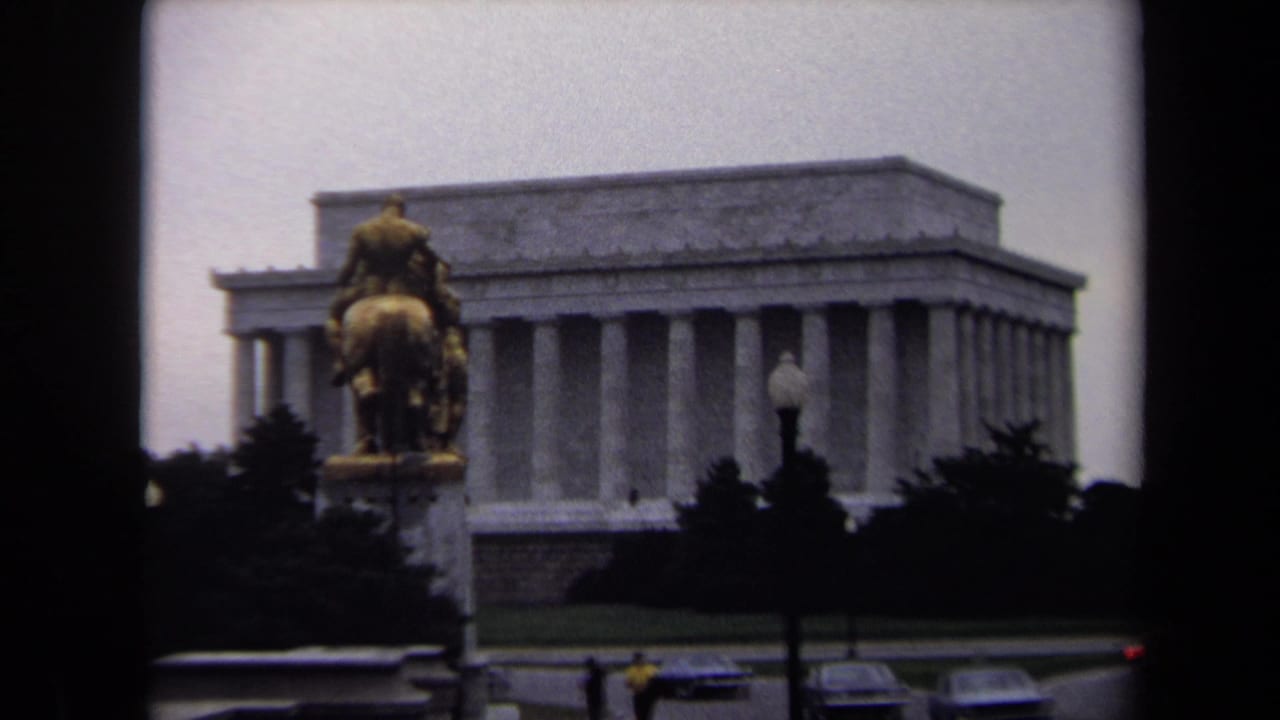 Wide view of the Lincoln Memorial with an equestrian statue, trees, streetlamps, and cars in the foreground.