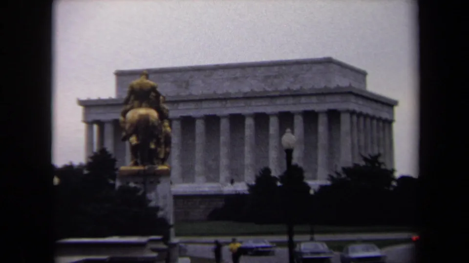 1970 8mm view of the Lincoln Memorial in Washington, DC, framed with an equestrian statue in front and traffic elements near the lower edge.