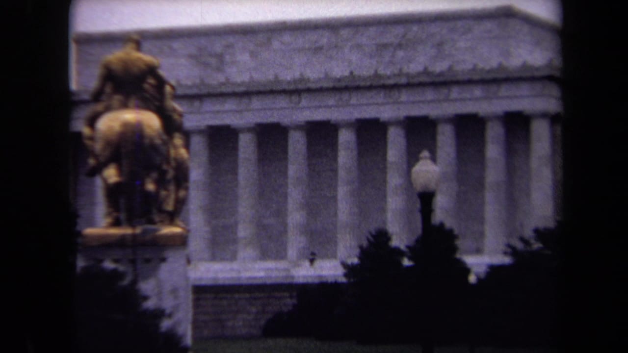 Closer view of the Lincoln Memorial facade with the equestrian statue at left and trees below.