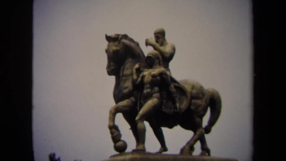 Wider 1970 Washington, DC 8mm view of a bronze equestrian statue with two human figures on a pedestal against a pale sky.