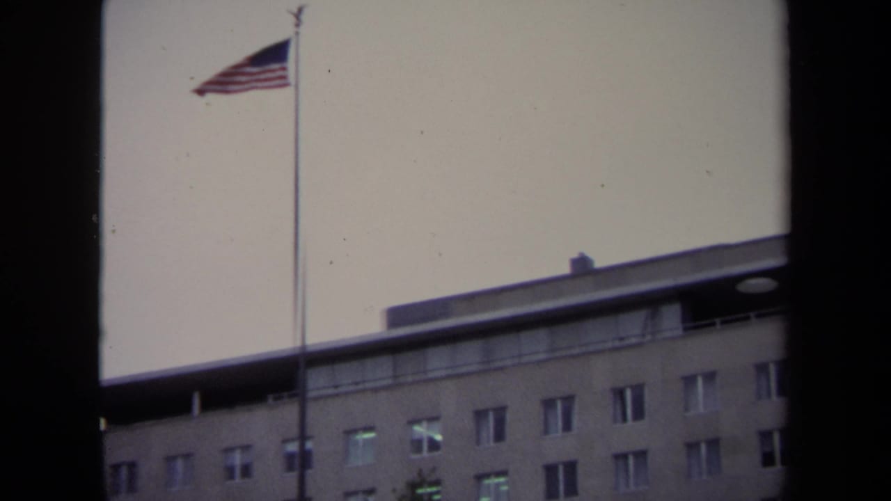 American flag above a large multi-story building facade.