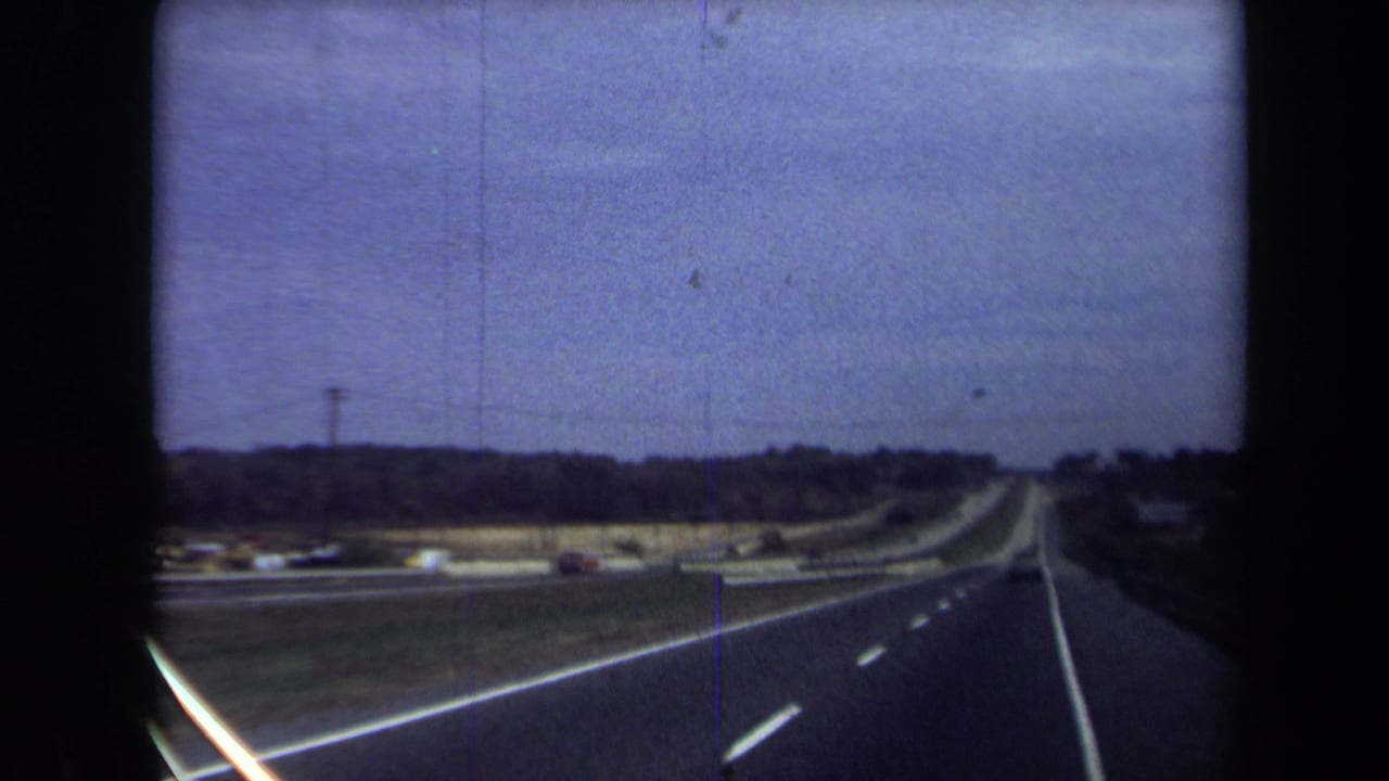 1970 8mm home-movie view from a moving vehicle on a Washington, DC-area highway beneath a purple-blue sky.