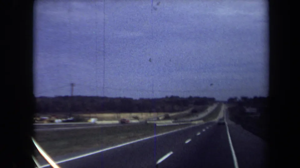1970 8mm home-movie view from a moving vehicle on a Washington, DC-area highway beneath a purple-blue sky.
