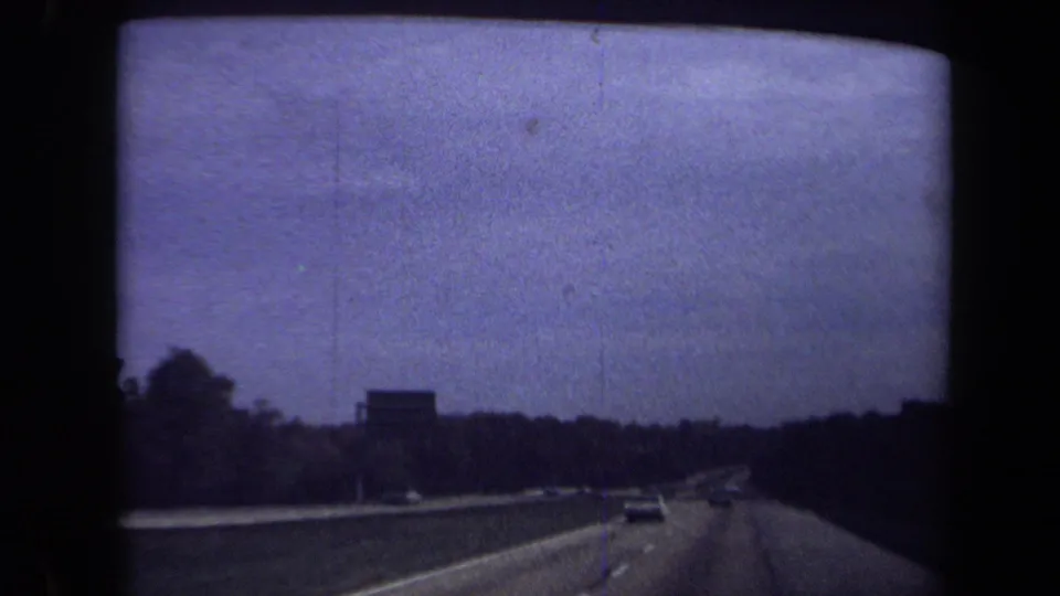 Washington, DC-area highway footage from 1970 shows a distant sign, cars ahead, and heavy 8mm grain.