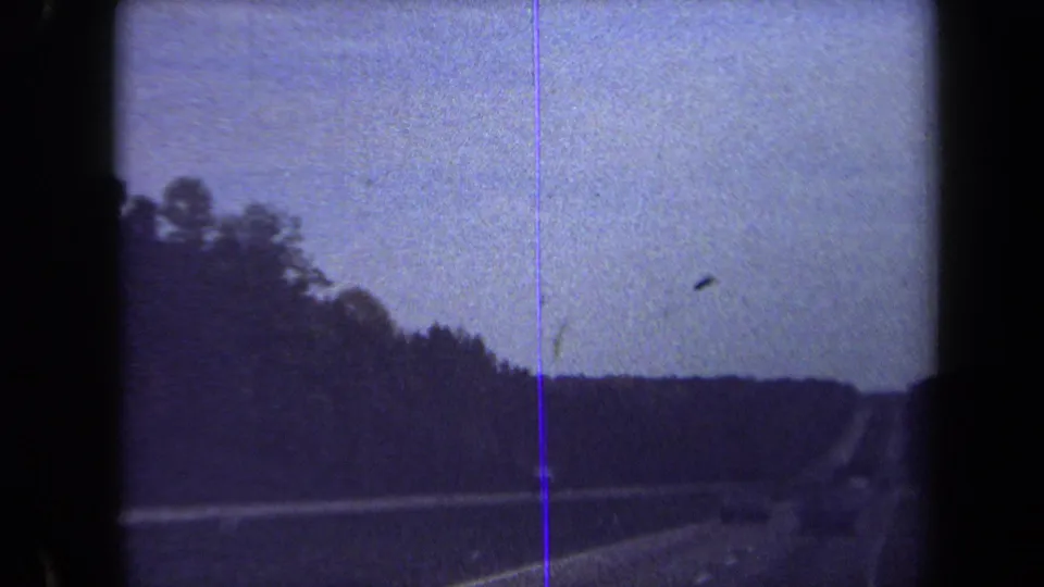 A brief 1970 8mm road-travel frame shows a Washington, DC-area highway, wooded horizon, and physical film marks.