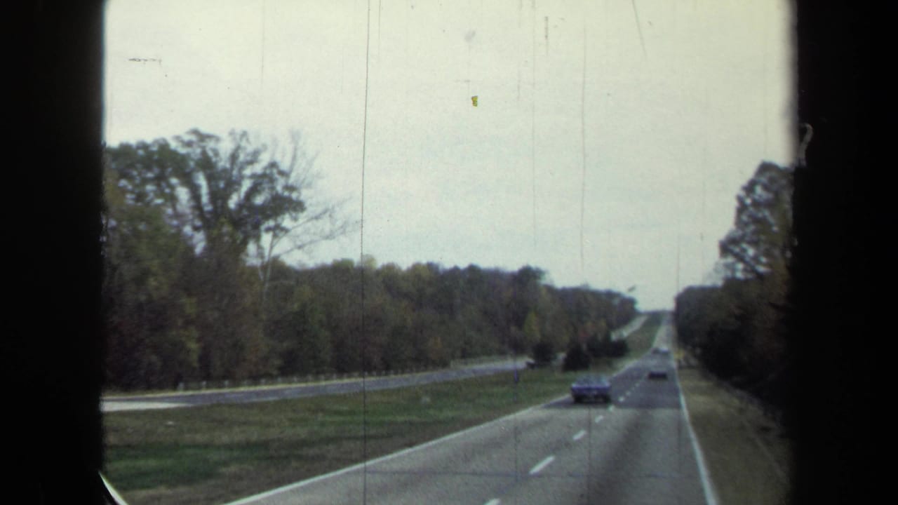 1970 8mm view from a moving vehicle on a wooded divided highway in the Washington, DC area, with cars traveling both directions.