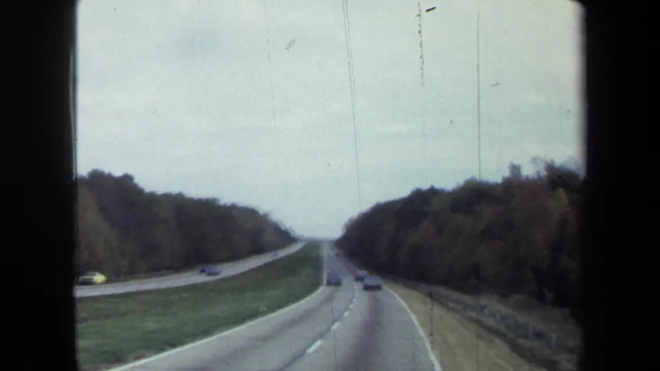 The final 1970 frame holds on a divided highway through wooded surroundings, filmed from a moving car in the Washington, DC area.